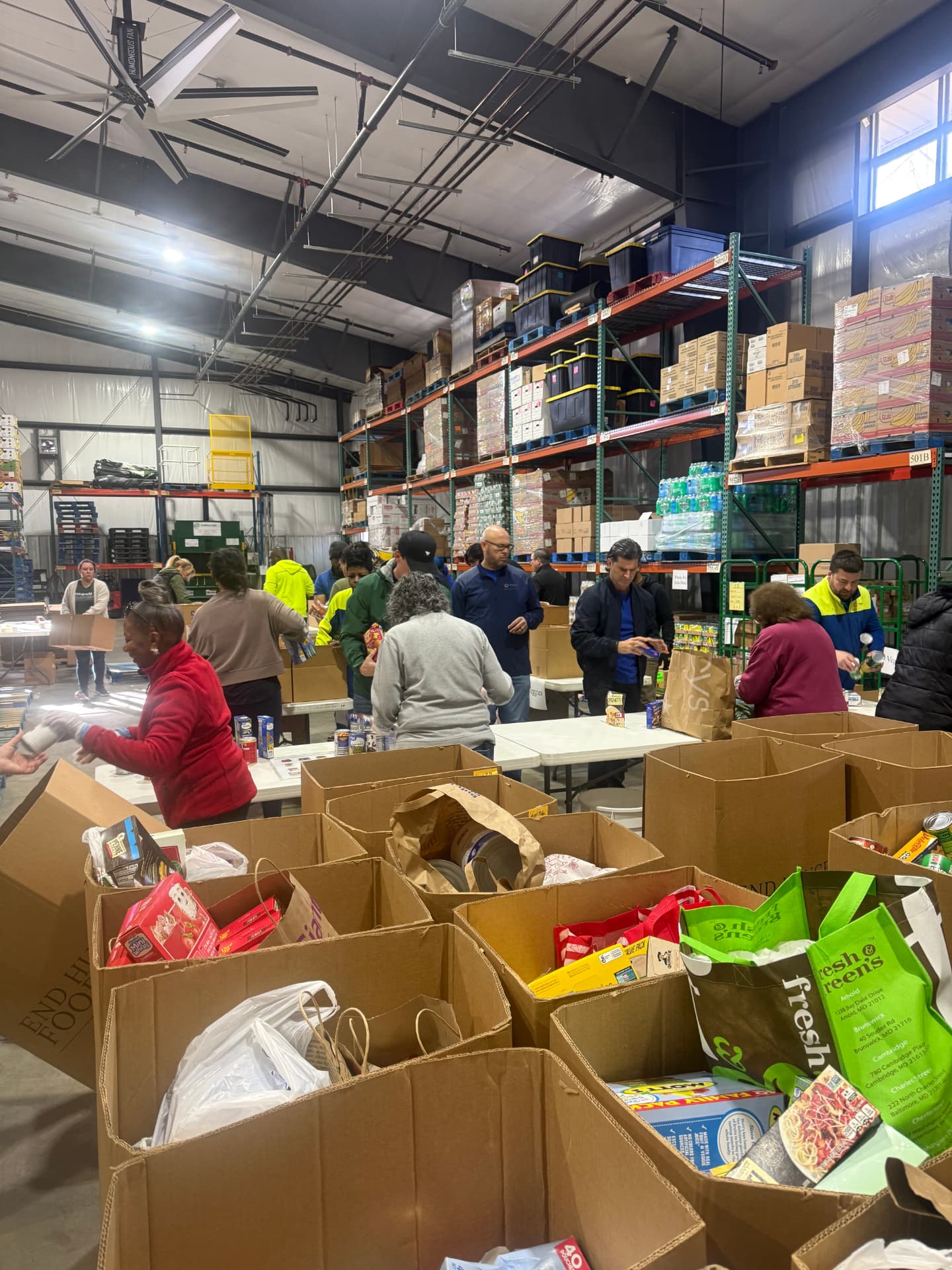Volunteers filling boxes with groceries at the End Hunger Food Bank warehouse